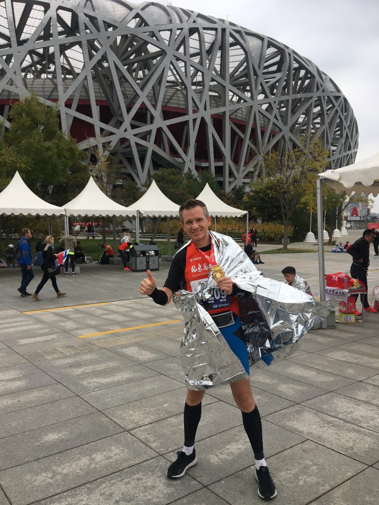 zum Bild: Karl Kicker vor dem Olympiastadion (Vogelnest) in Peking nach dem Peking-Marathon 2019. Foto: Karl Kicker.